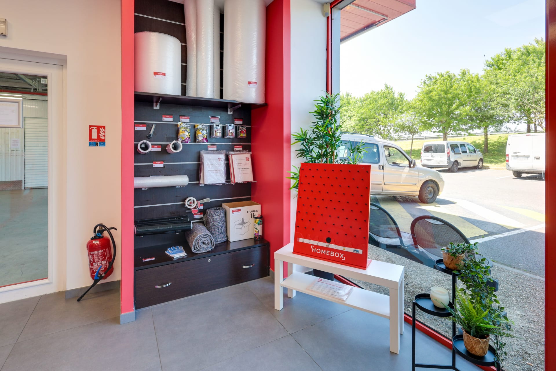 Espace fournitures de déménagement avec rouleaux de papier bulle, cartons et présentoir rouge du centre HOMEBOX Roissy