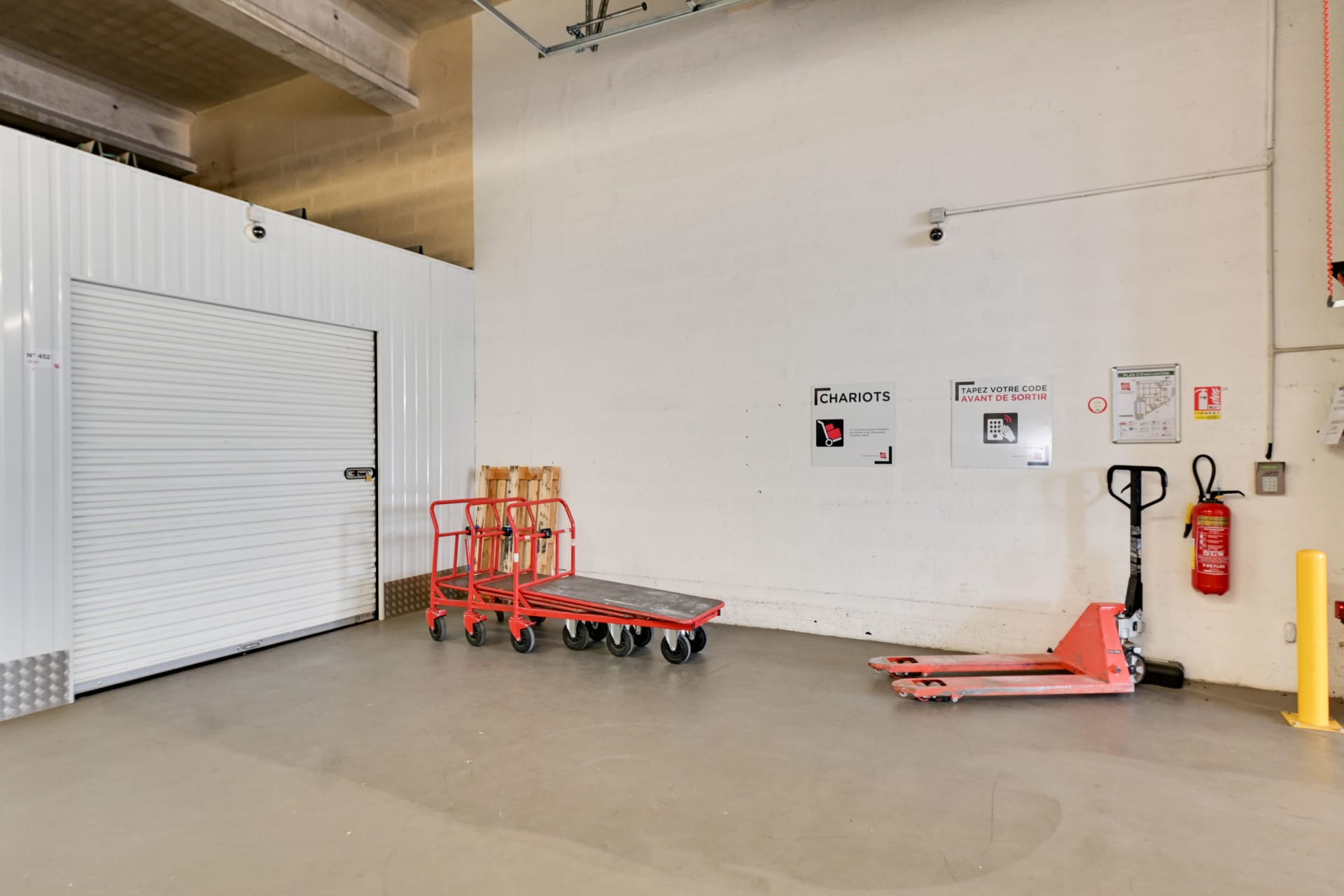 Zone de chargement intérieure avec chariots, transpalette et porte sectionnelle blanche du centre HOMEBOX Marseille - Plombières