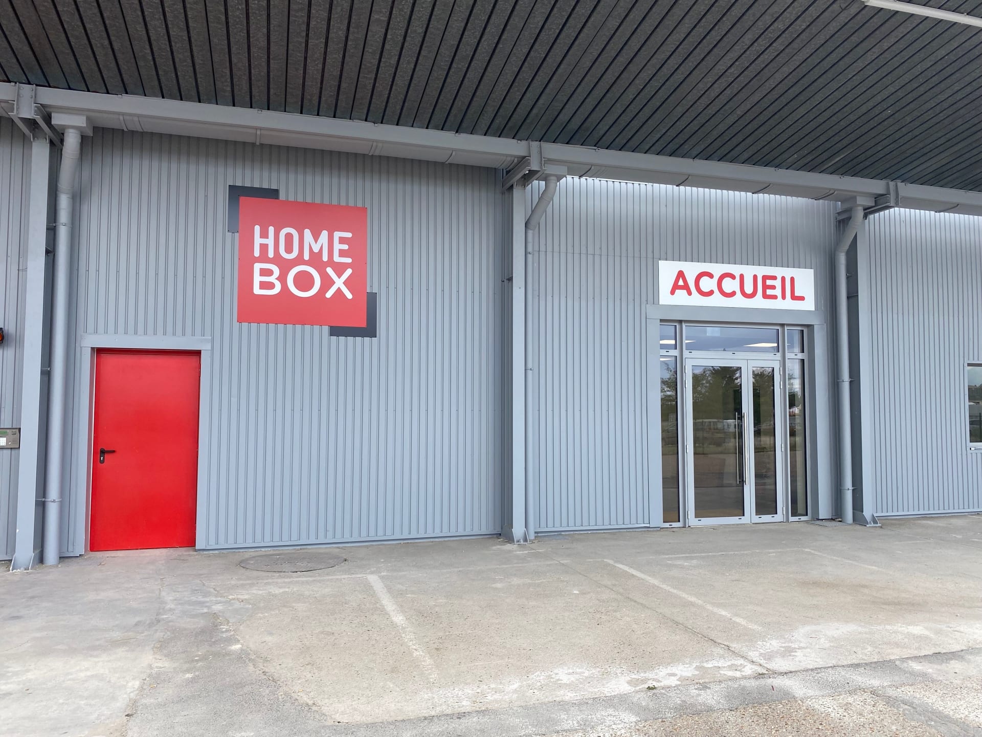 Façade grise avec logo HOMEBOX rouge et entrée vitrée Accueil, HOMEBOX Orléans Nord, 165 Impasse des Moulins à Saran