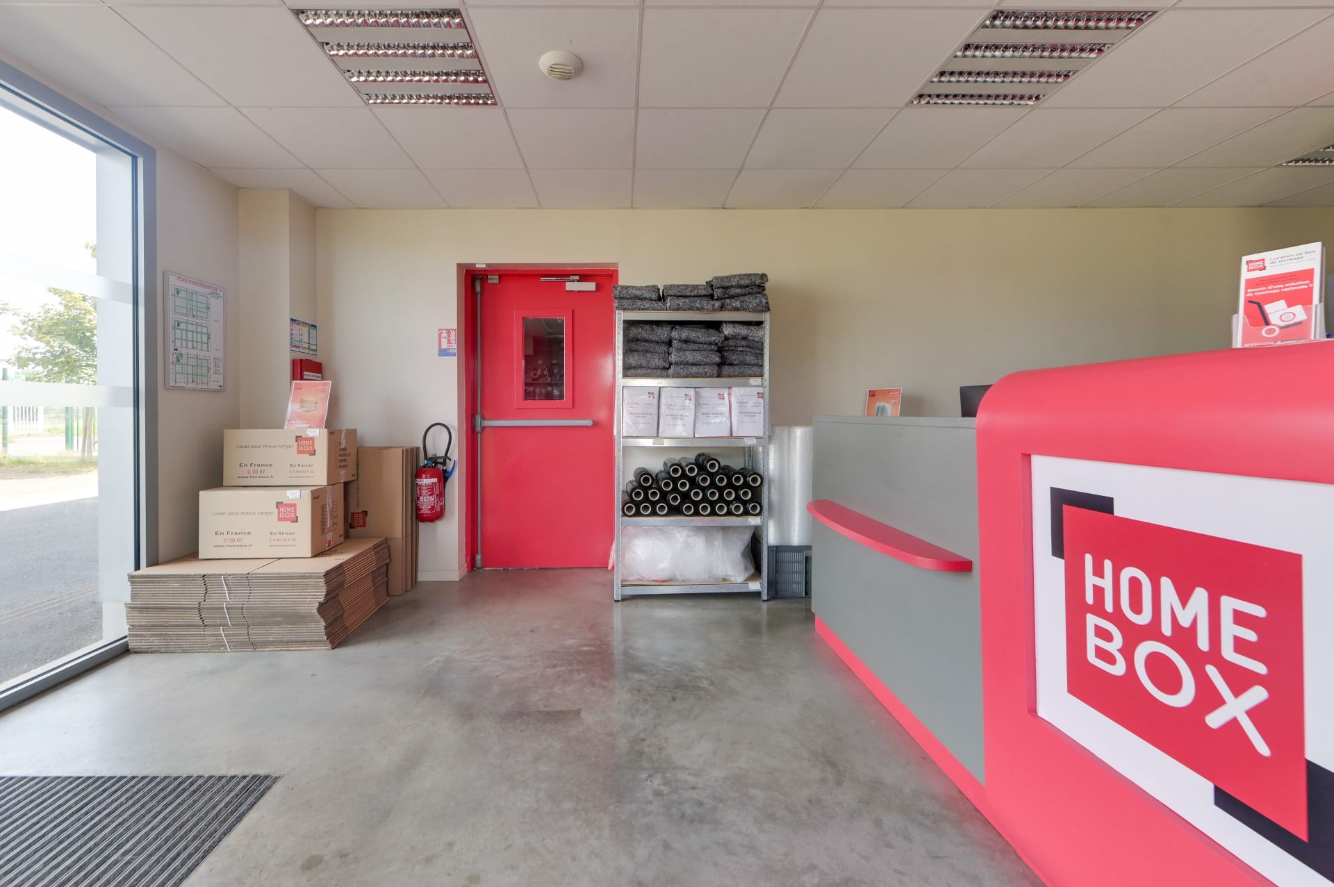 Boutique d'accueil avec comptoir rouge, cartons et matériel d'emballage du centre HOMEBOX Pau