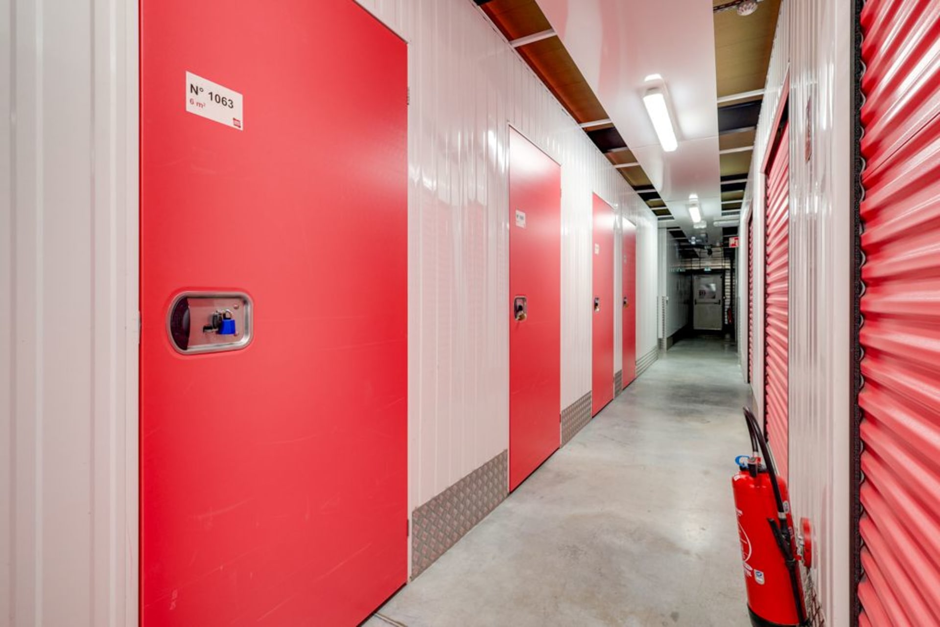 Couloir intérieur du centre HOMEBOX Carrières-Chanteloup montrant des box de stockage à portes rouges et blanches.