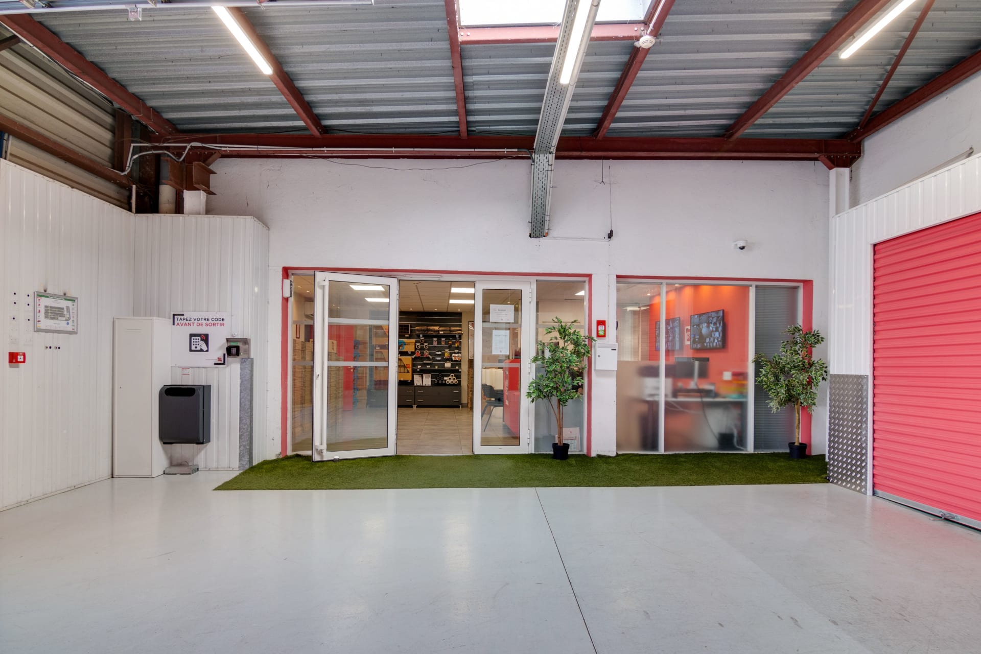 Espace intérieur avec entrée vitrée vers l'accueil et porte de box rouge du centre HOMEBOX Montpellier