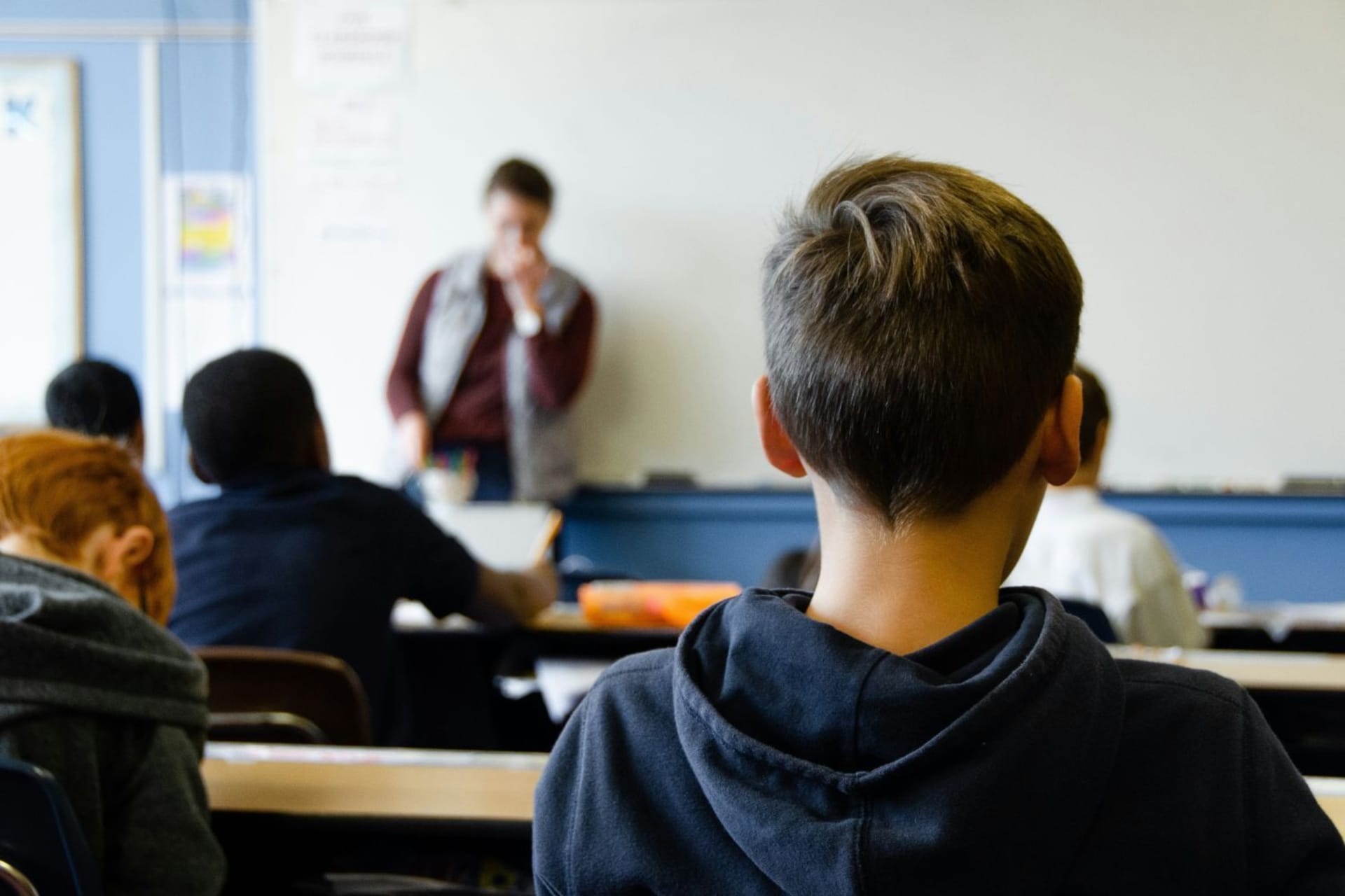 Enfant de dos portant un sweat à capuche bleu marine et assistant à un cours