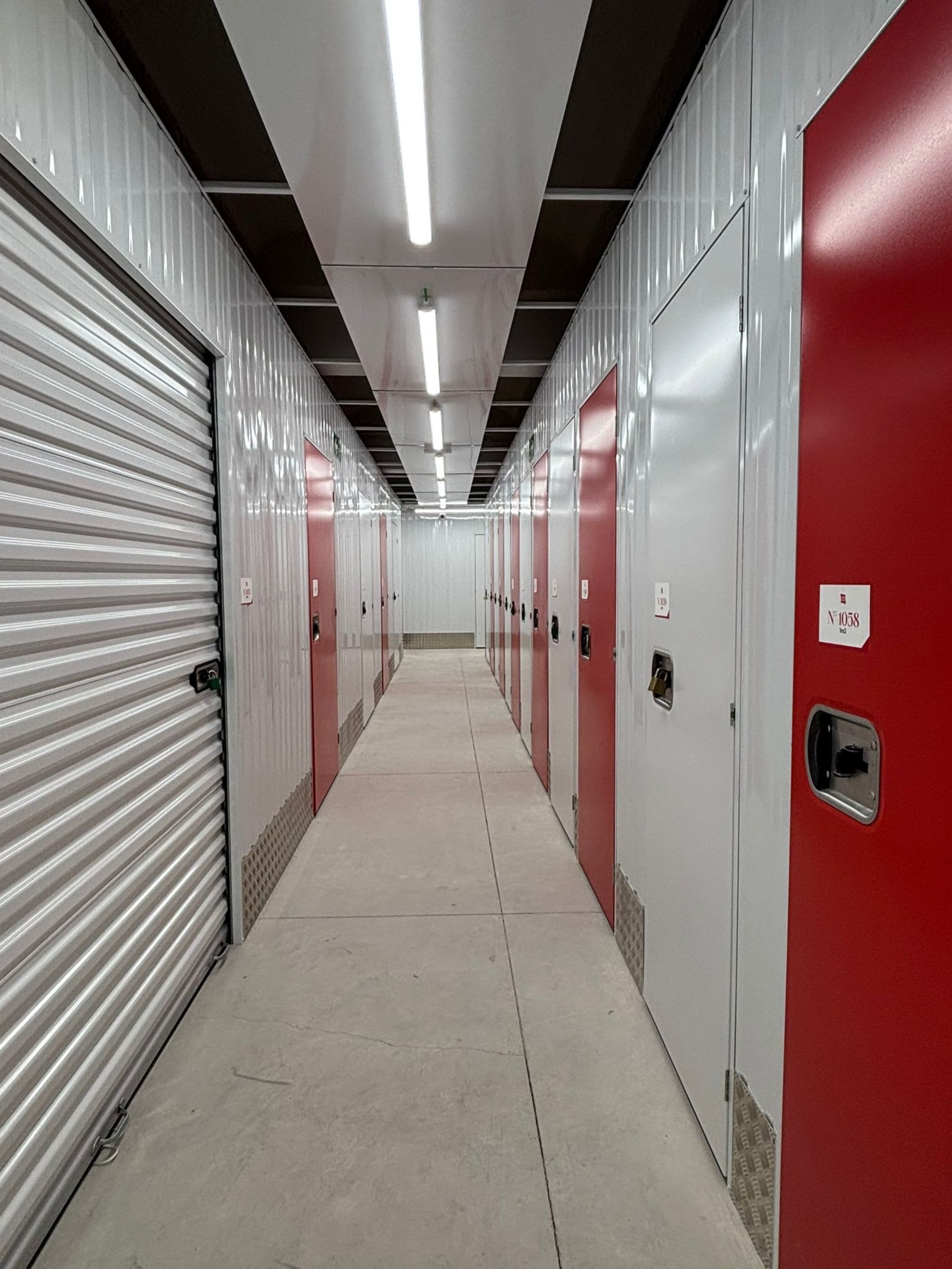 Pasillo interior con puertas de trasteros rojos y blancos del centro HOMEBOX Barcelona Esplugues