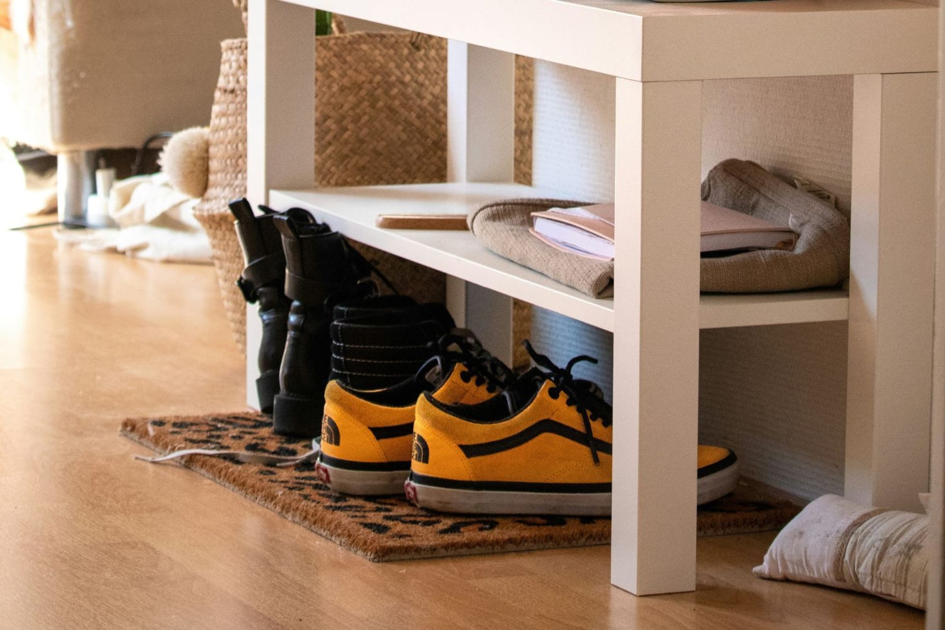 Paires de chaussures glissées sous un banc dans une entrée