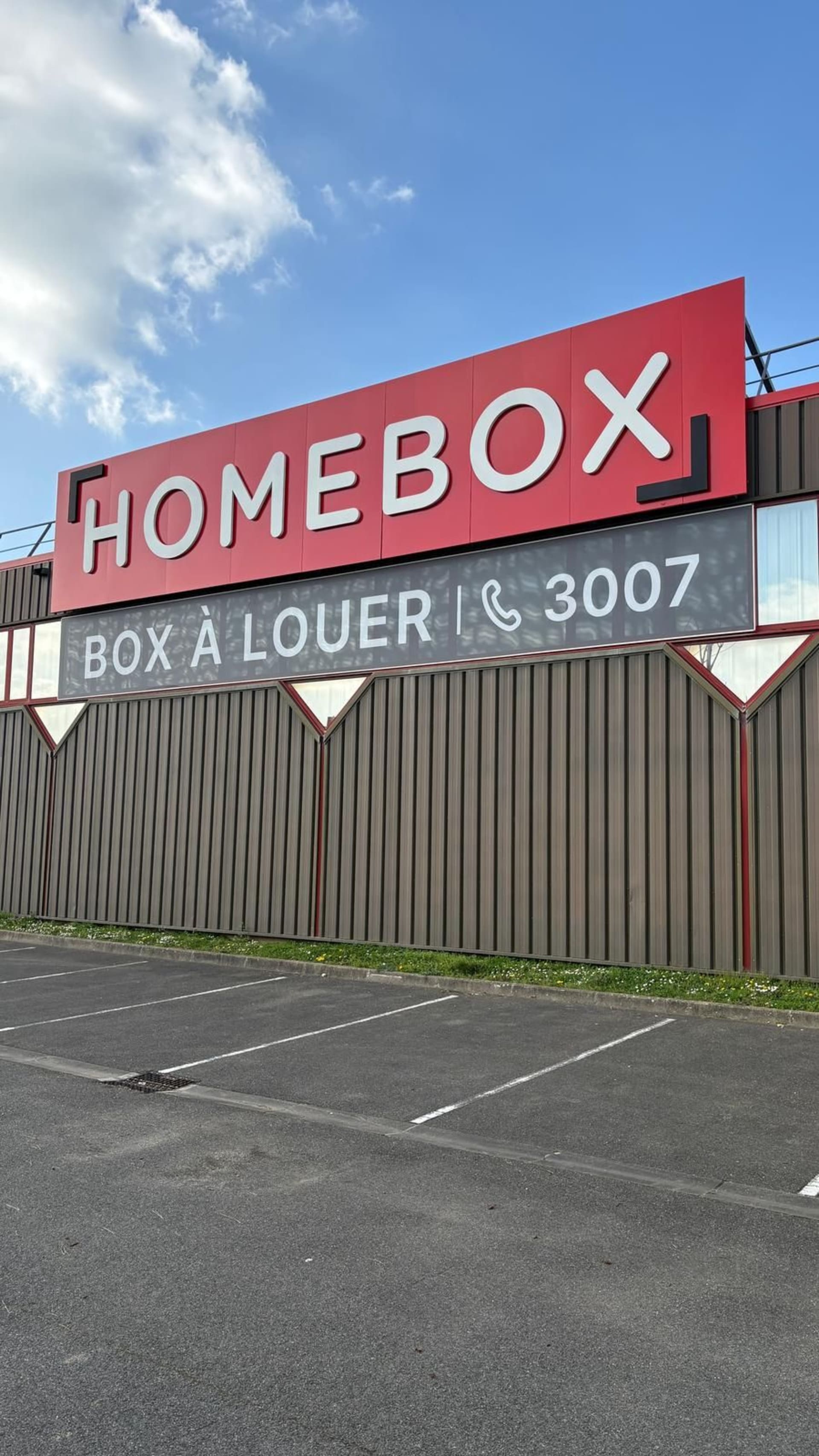 Large red Homebox sign with Box à louer and phone number above an empty parking lot at HOMEBOX Collégien, 9 allée du Clos des Charmes, Collégien