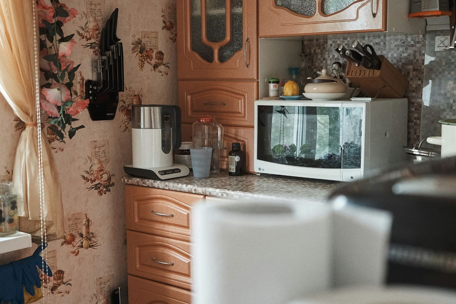 Micro-ondes dans une cuisine vintage avec mobilier en bois et tapisserie à fleurs