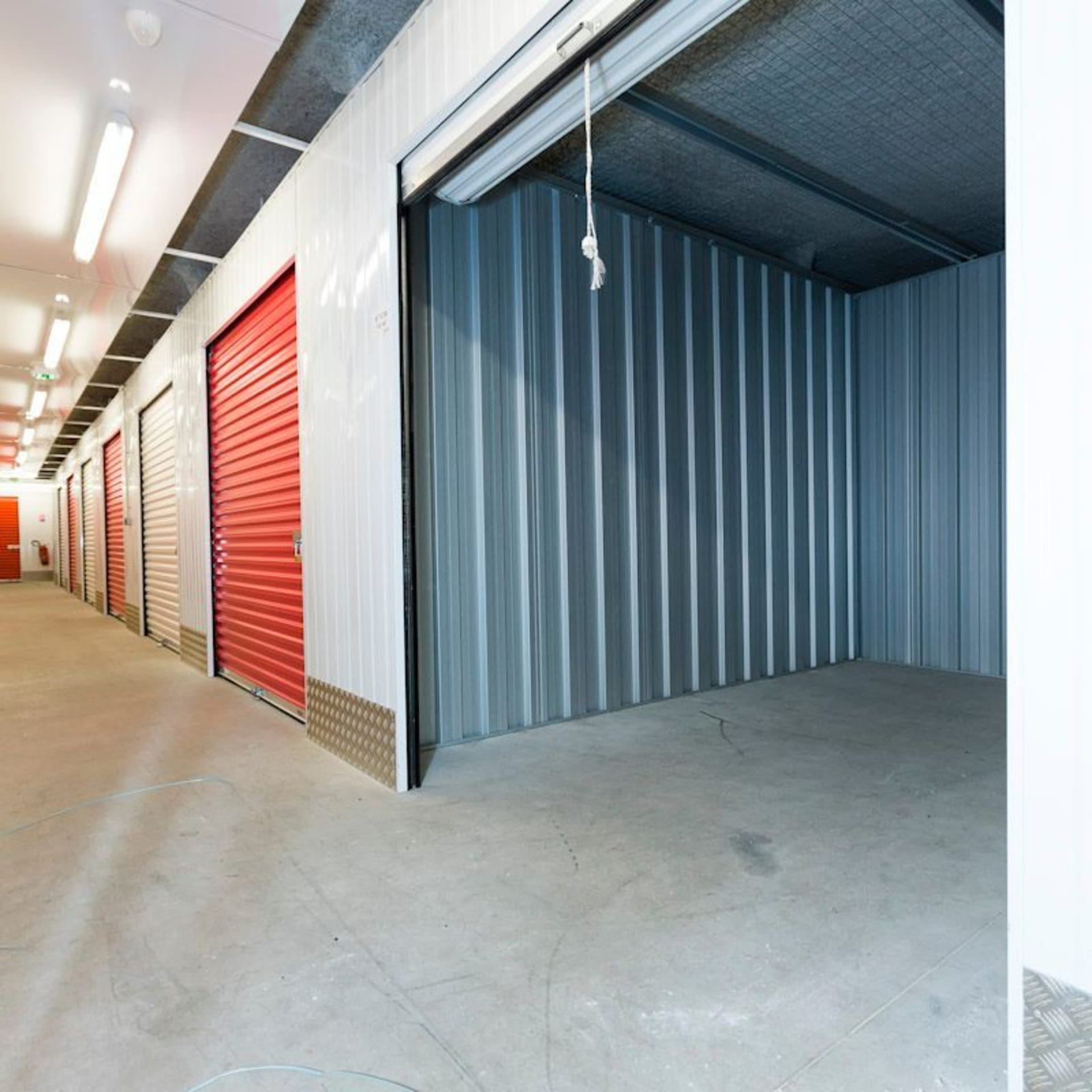 Box de stockage avec porte roulante rouge dans le couloir intérieur du centre HOMEBOX Bayeux.