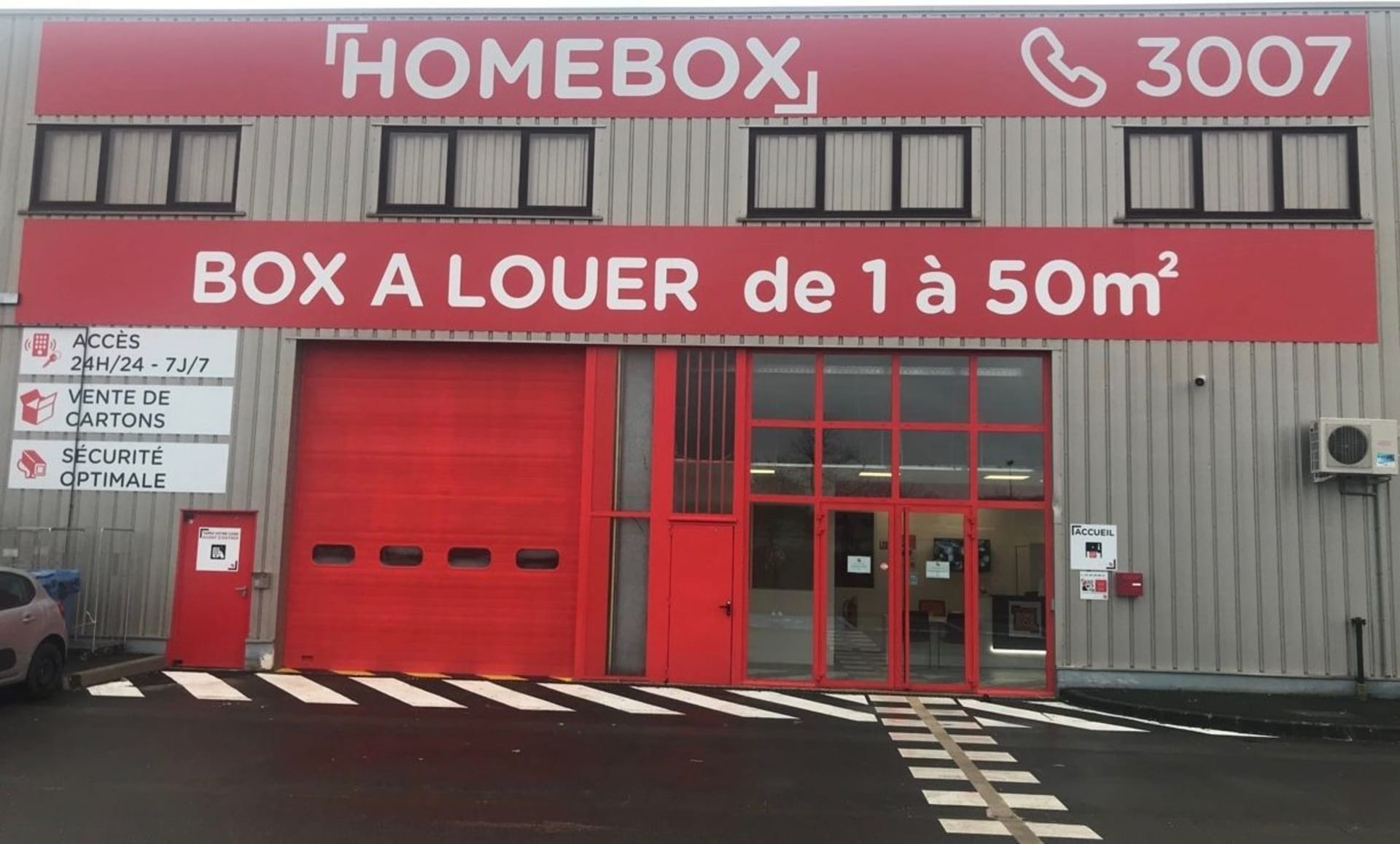 Façade principale du centre HOMEBOX Cholet, avec enseigne et portes rouges.