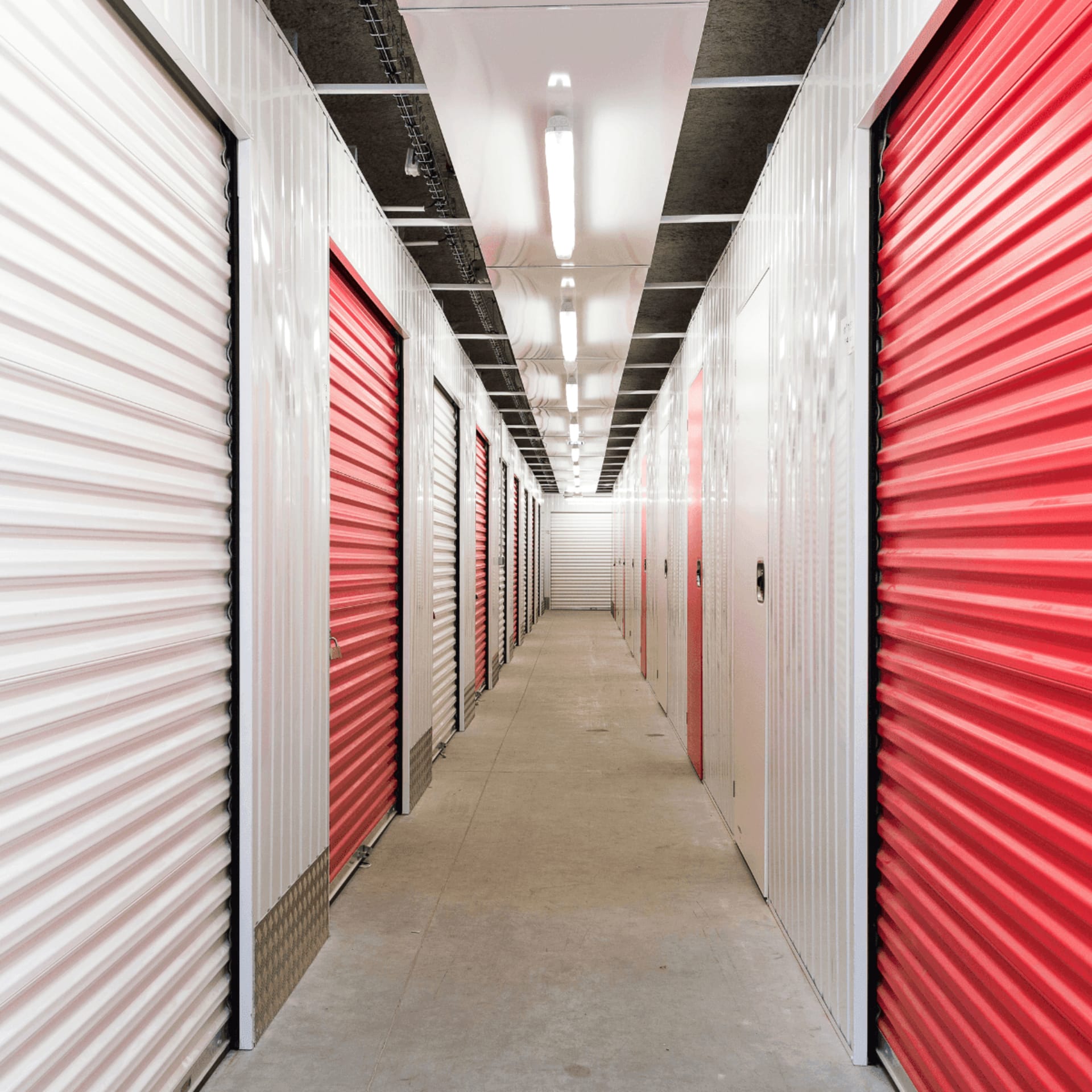 Couloir intérieur avec box rouges et blancs au centre HOMEBOX Corte.