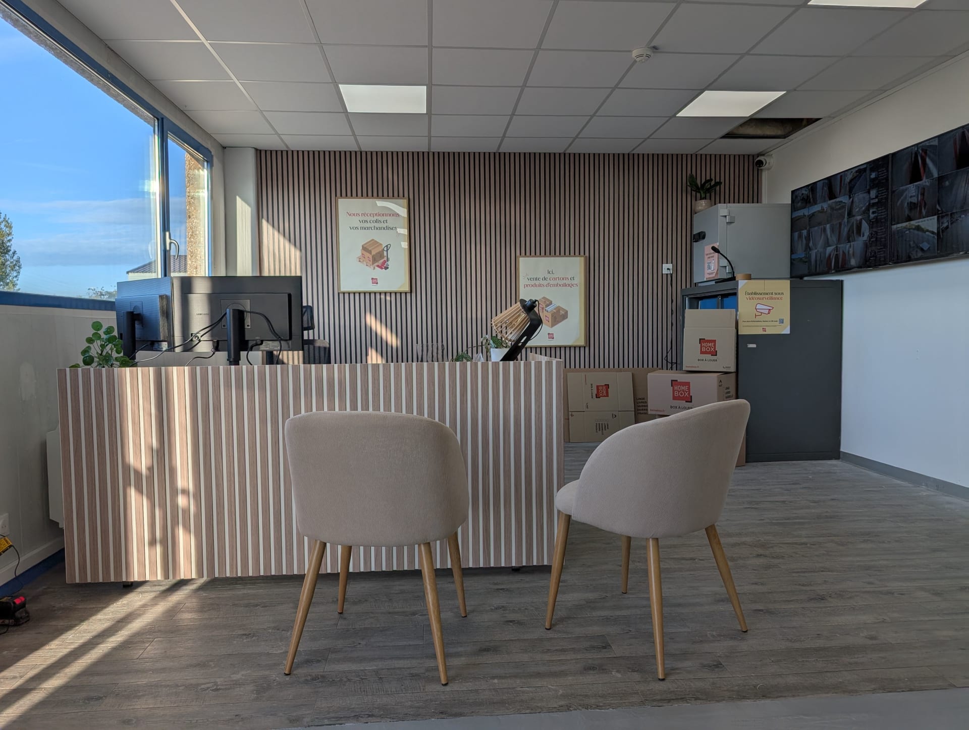 Espace d'accueil intérieur avec comptoir clair, fauteuils et cartons du centre HOMEBOX Dunkerque