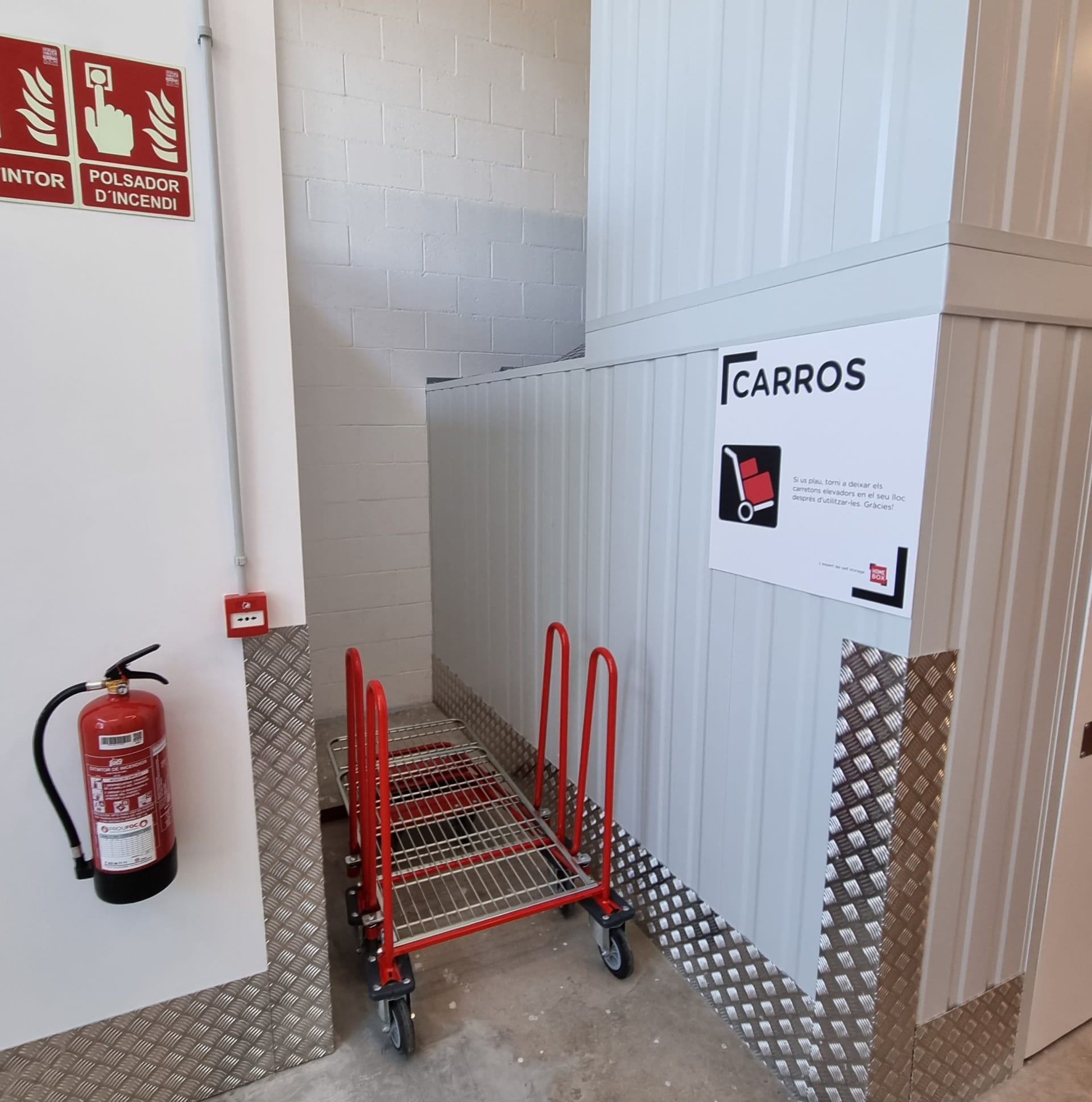 Trolley parking bay with red carts and fire extinguisher near safety signage at HOMEBOX Blanes