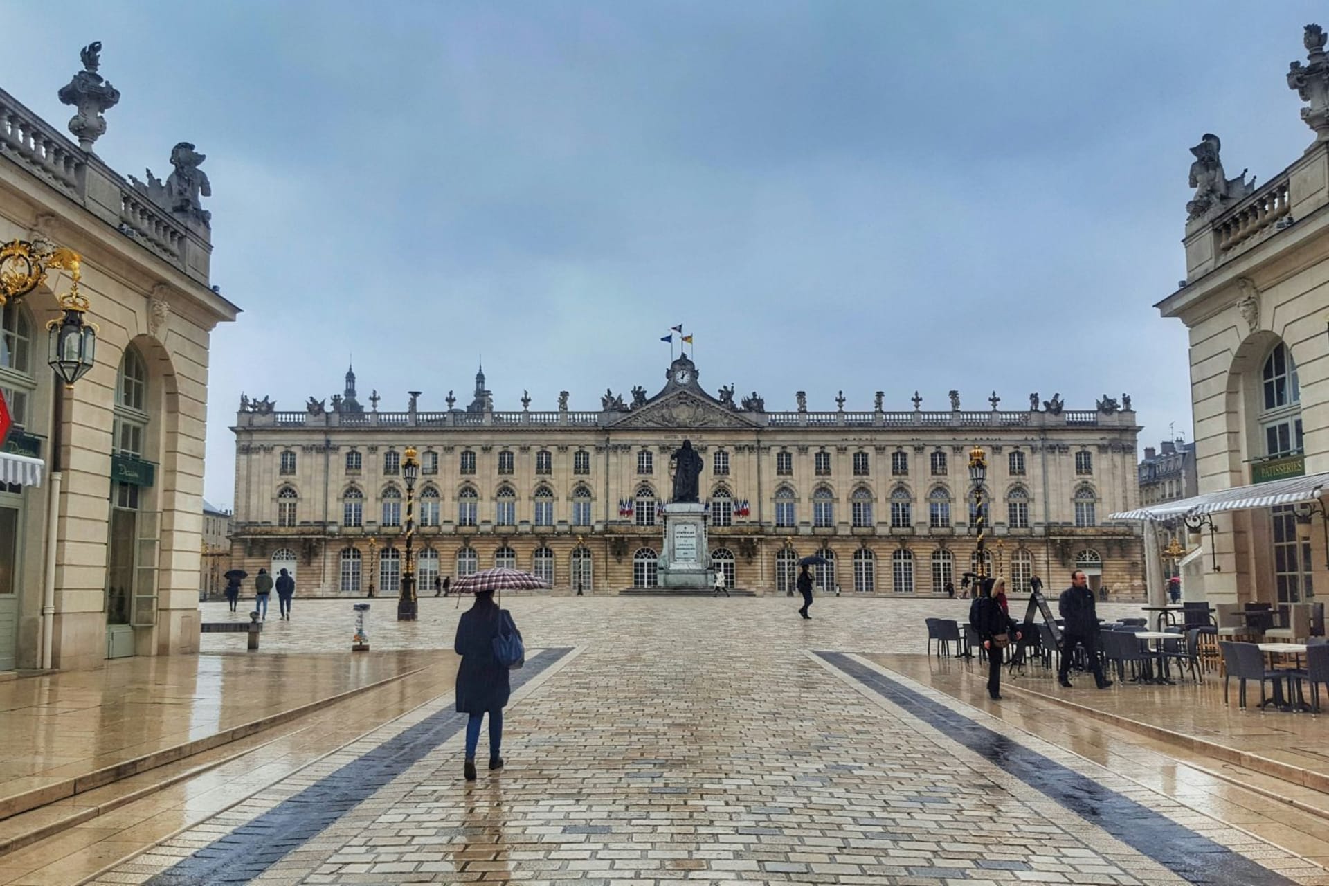 Place Stanislas par temps de pluie, peu de personnes et une terrasse à droite