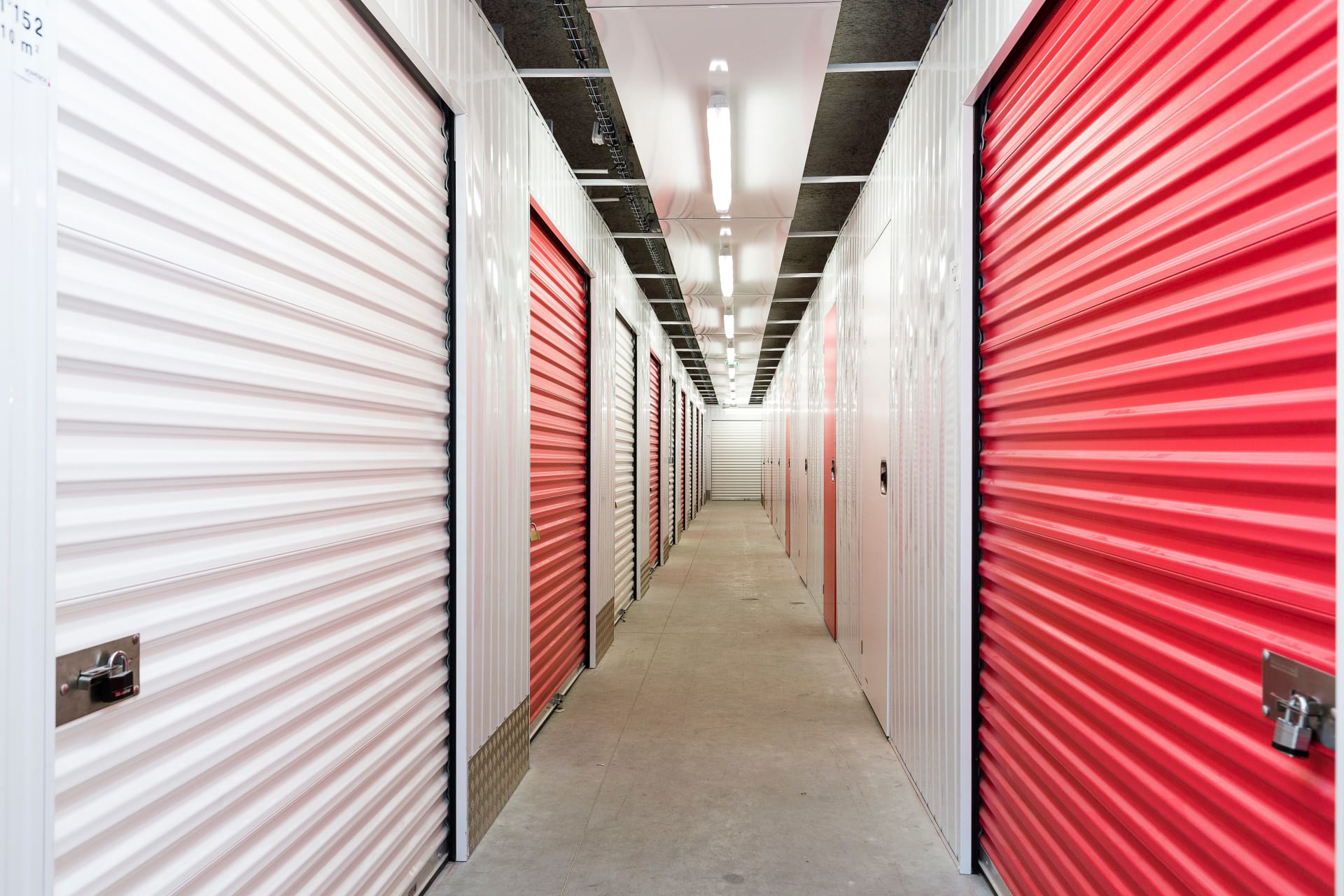 Couloir intérieur avec rangées de portes de boxes rouges et blanches du centre HOMEBOX Béthune