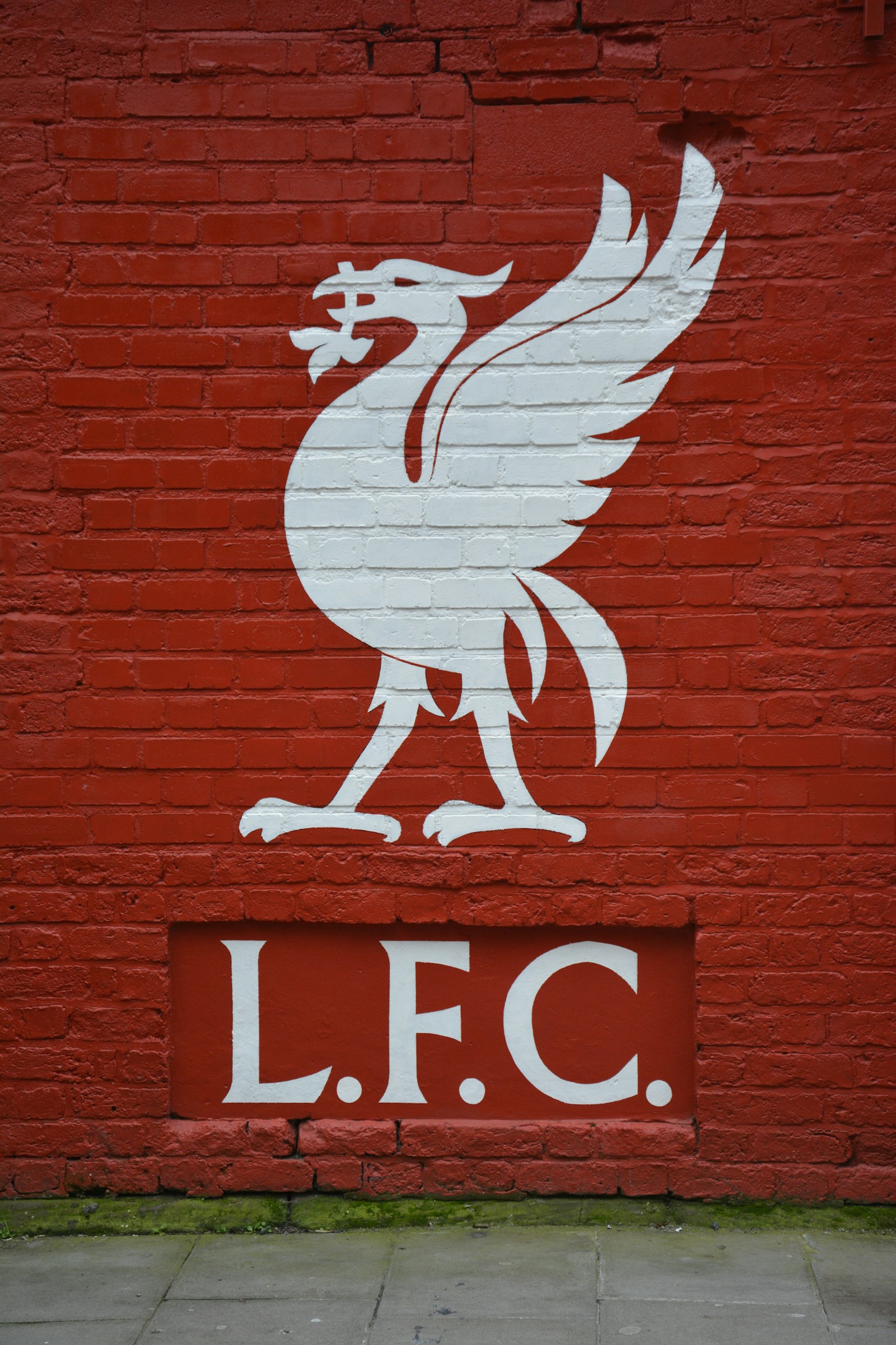 Liverbird logo and LFC on red brick wall at Anfield