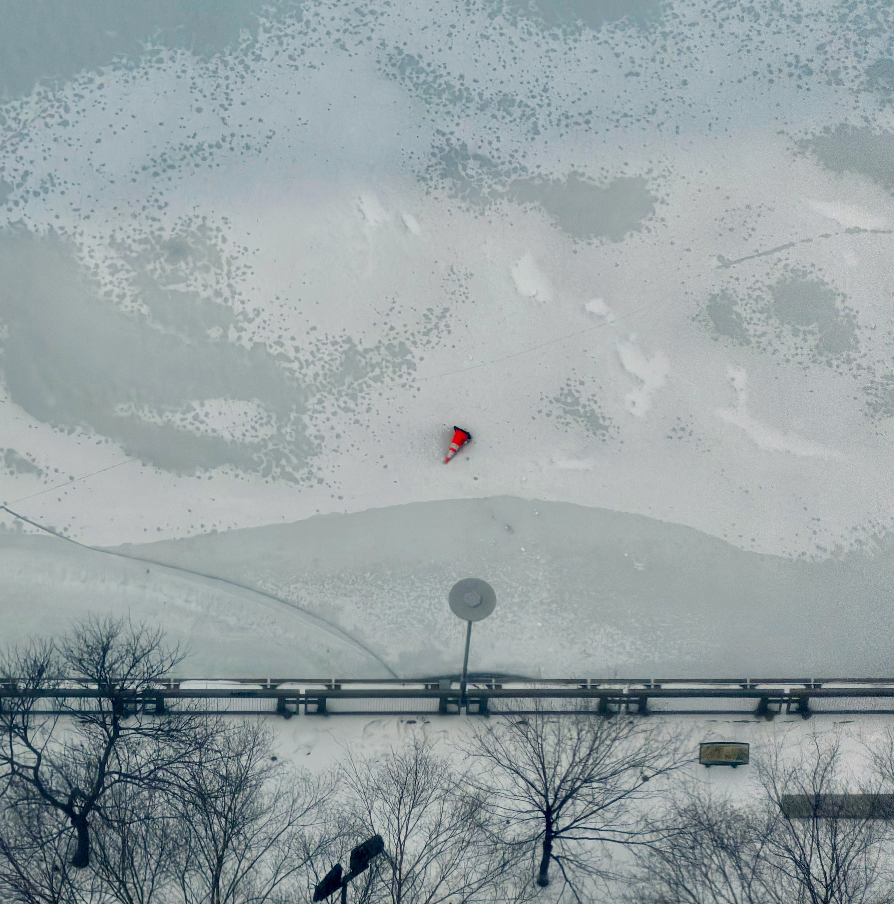 a small orange cone contrasting against the surface of an icy river