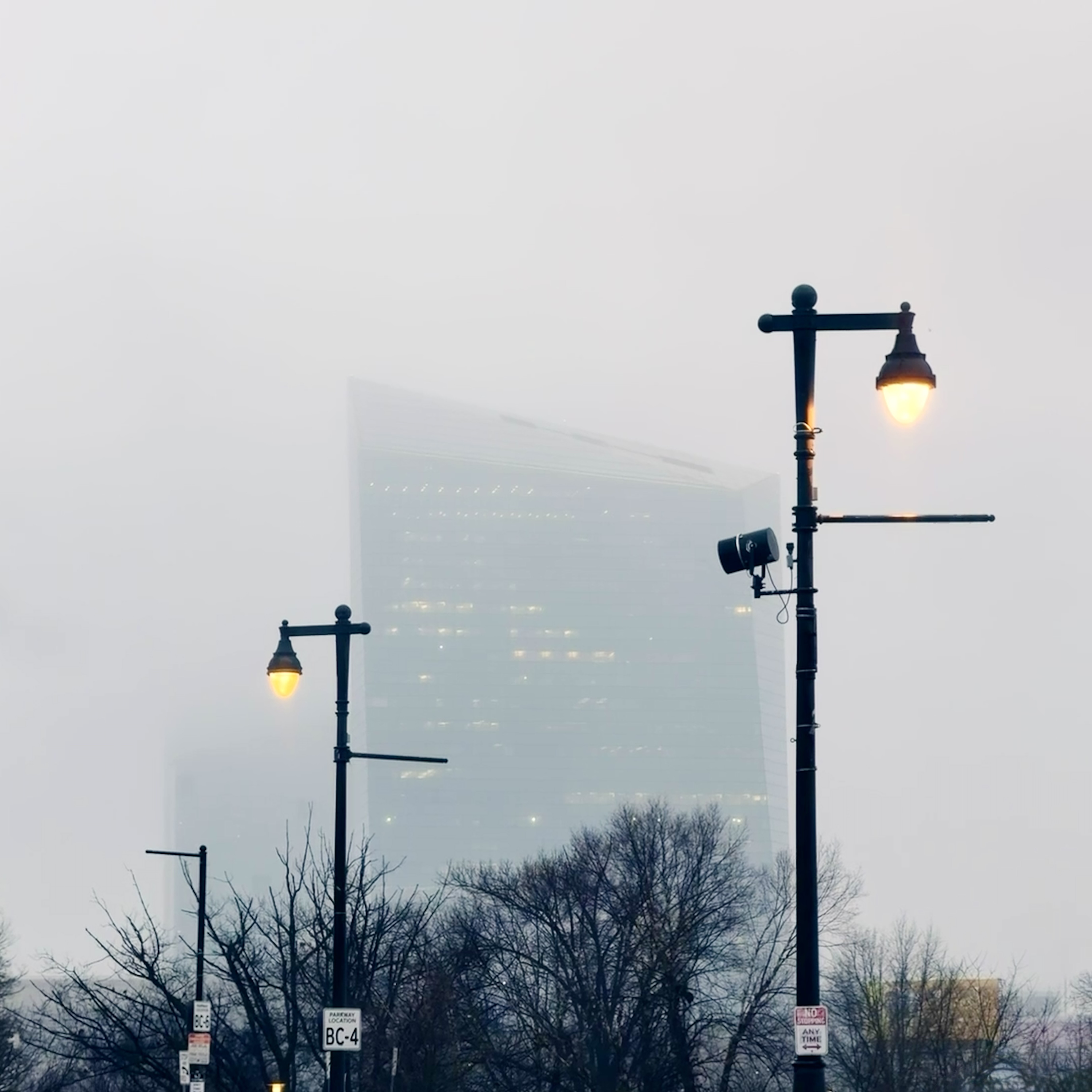a foggy building in the background, with orange lit streetlamps framing it