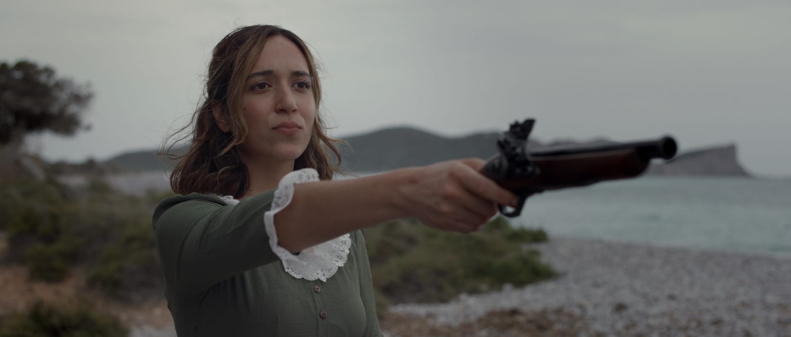 Actriz apuntando con una pistola de época en una escena de suspense