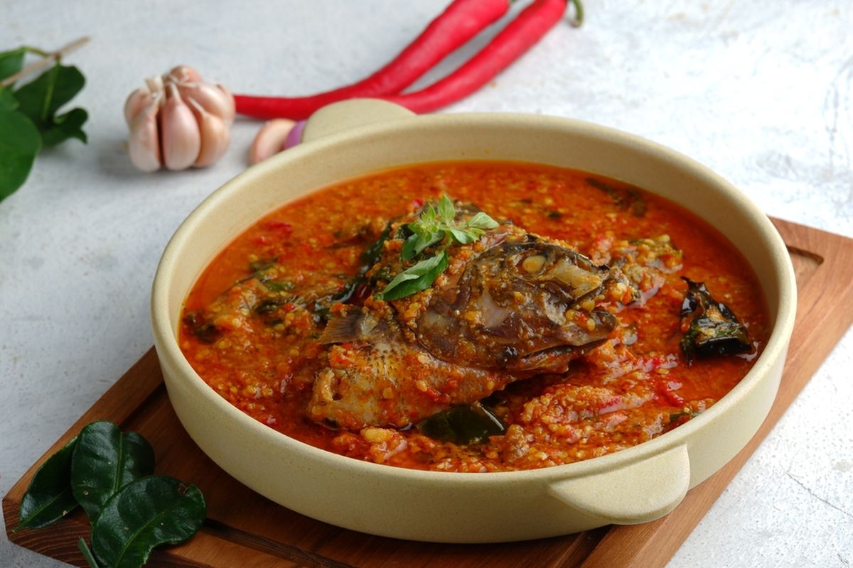 Ayam Tuturuga — ayam bakar khas Manado dengan bumbu rica-rica pedas, kulit gosong kecokelatan, disajikan dengan lalapan segar dan sambal dabu-dabu di atas piring tradisional