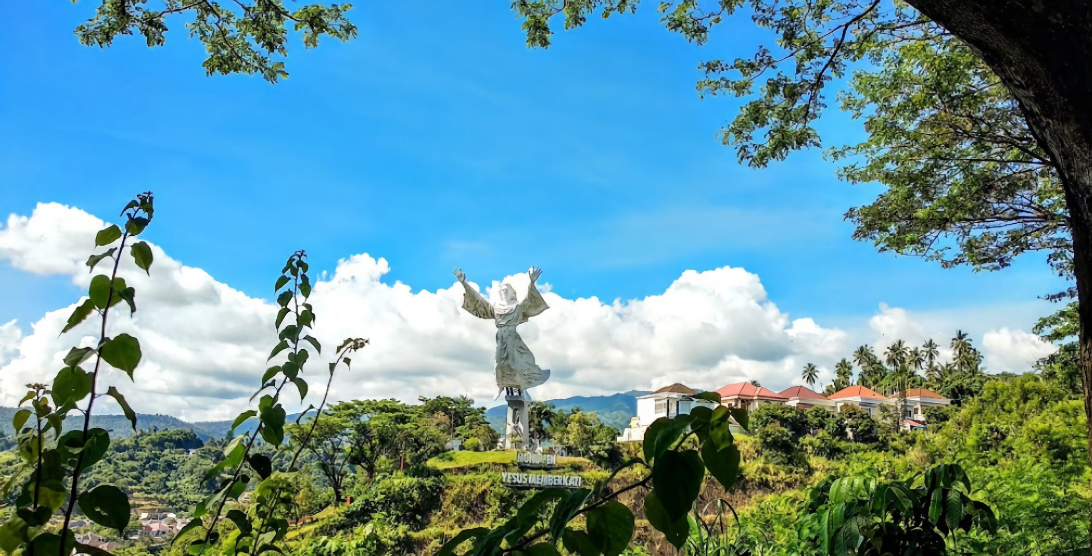 Patung Yesus Memberkati megah berdiri di puncak bukit dengan latar langit biru Manado Sulawesi Utara
