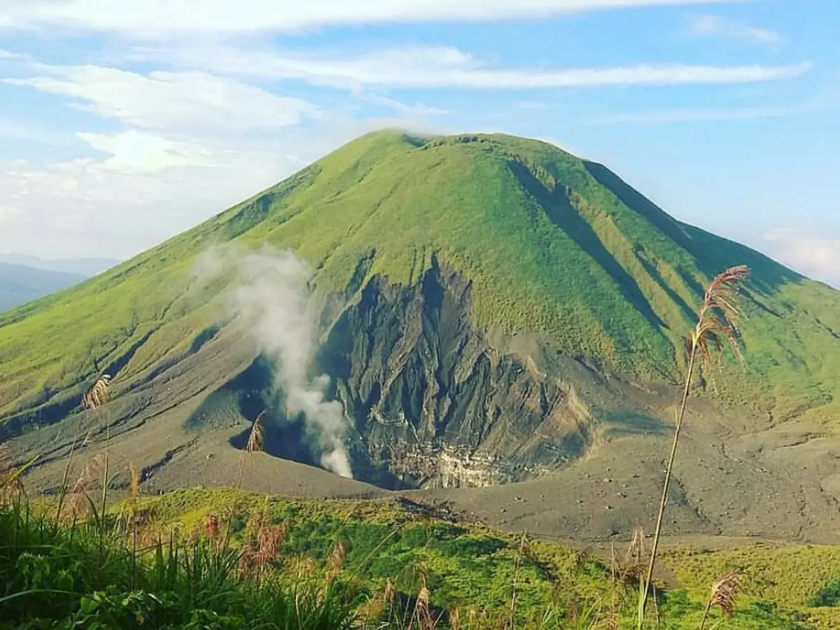 Pemandangan Gunung Lokon dari kejauhan dengan puncak yang diselimuti kabut