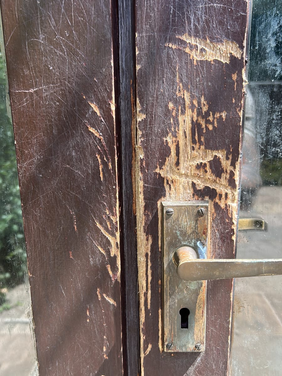 The timber French doors before work, the edges torn away
