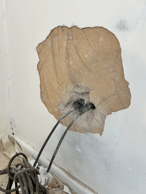 A large area of plaster missing around the cable entry, back to the backing coat and cracked across it