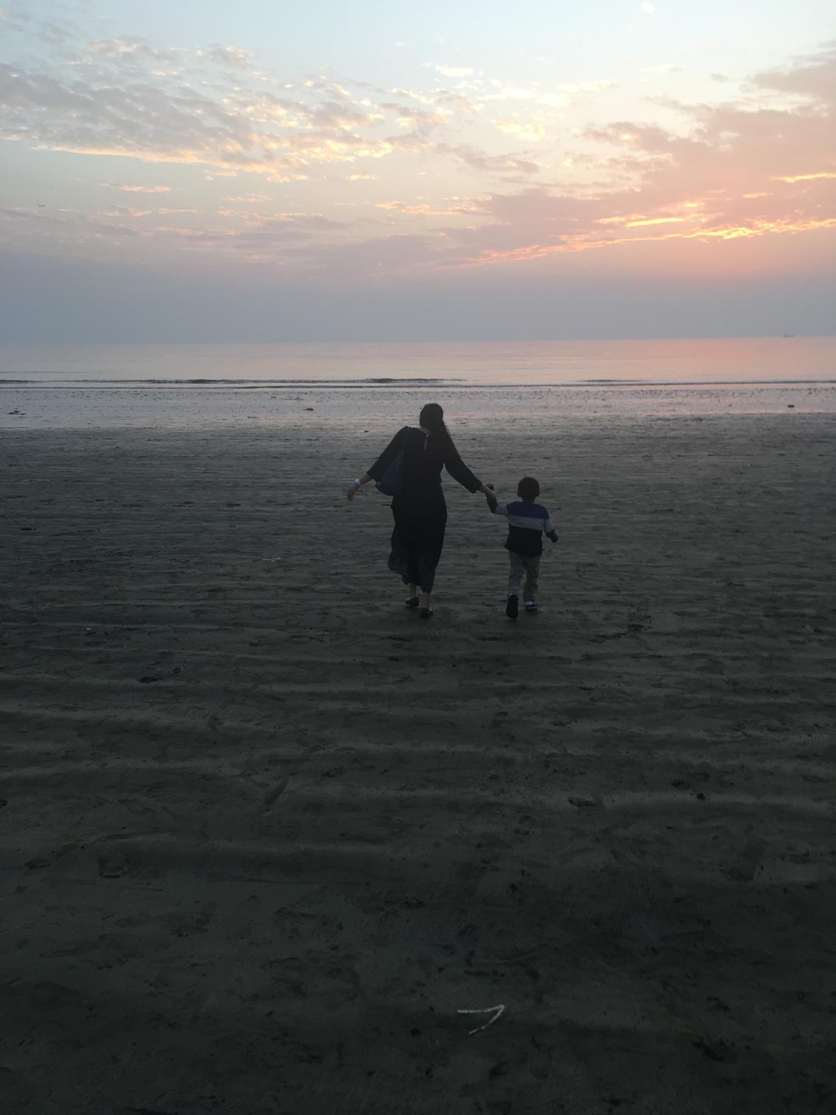 A mother and child walking into the sunset on a beach