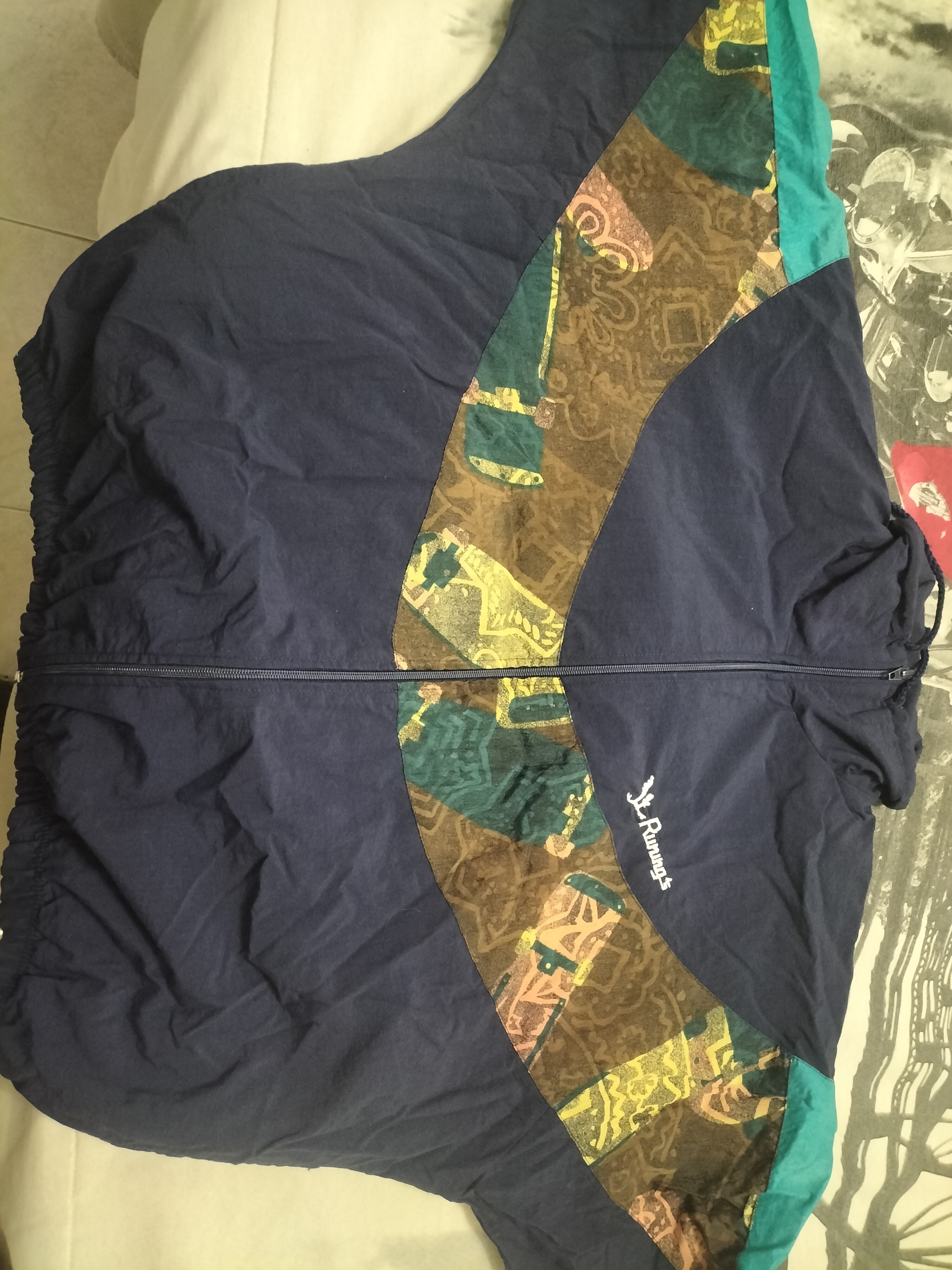 Dark blue bomber jacket with a colourful patter spanding across the chest and arms.