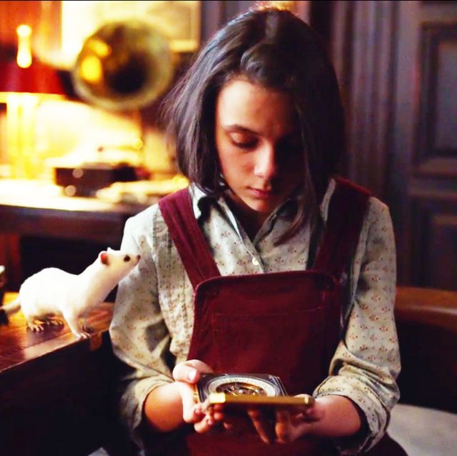 Lyra holding the alethieometer while Pan watches.