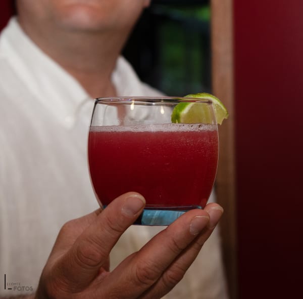 Cocktail aux fruits rouges garni d'une rondelle de citron vert tenu en main, photographie de boissons par Delphine Lecomte à Nantes