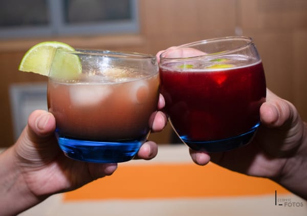 Deux convives trinquant avec des cocktails colorés garnis de citron vert lors d'un événement, photographie d'ambiance