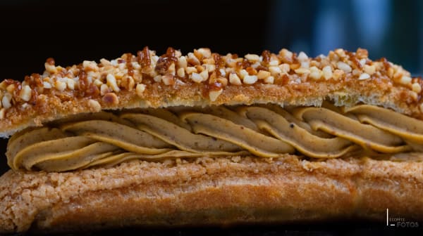 Gros plan macro sur un éclair praliné garni de crème torsadée et nappé de noisettes caramélisées, photographie culinaire à Nantes