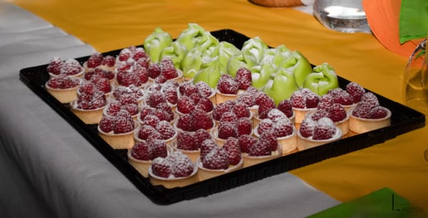 Plateau de tartelettes aux framboises saupoudrées de sucre glace et raisins verts, buffet dessert événementiel