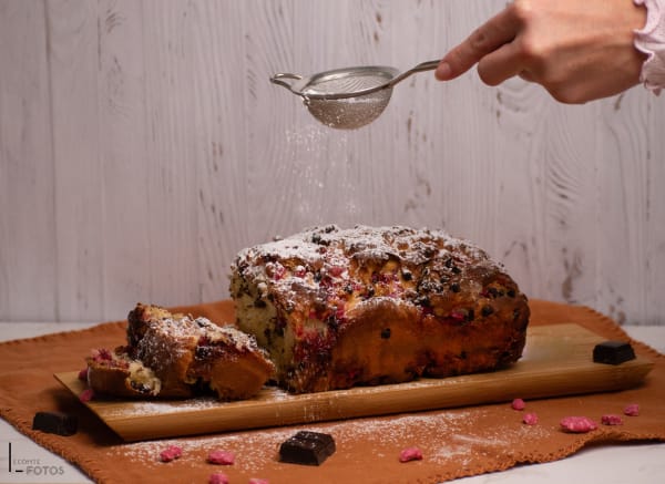 Cake aux pralines roses et pépites de chocolat saupoudré de sucre glace sur planche en bois
