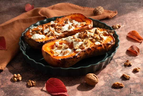 Butternut rôti farci au fromage frais et noix dans un plat en céramique vert, ambiance automnale