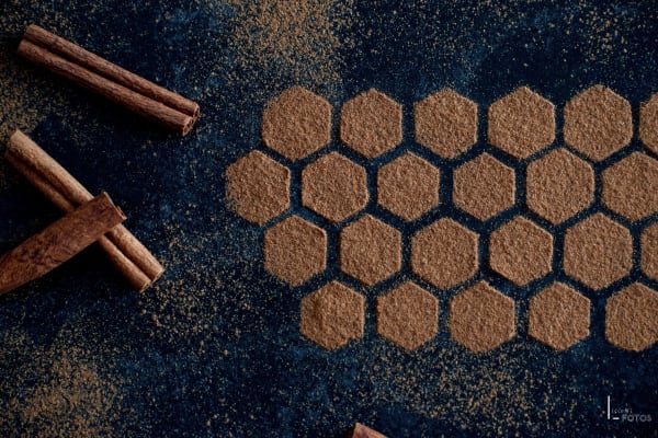 Motif nid d'abeille en poudre de cannelle avec bâtons de cannelle sur fond sombre