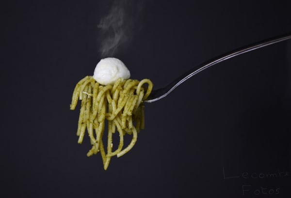 Fourchette suspendue enroulée de spaghettis au pesto avec boule de mozzarella fumante
