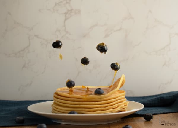 Pile de pancakes avec myrtilles et sirop d'érable en lévitation au-dessus, photographie créative