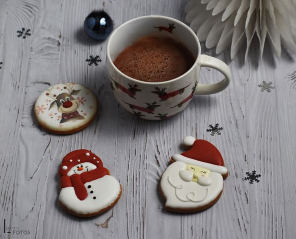 Sablés de Noël décorés au glaçage royal en forme de renne, bonhomme de neige et Père Noël avec chocolat chaud