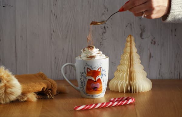 Tasse renard de chocolat chaud avec chantilly et filet de caramel, sucre d'orge et décor de Noël