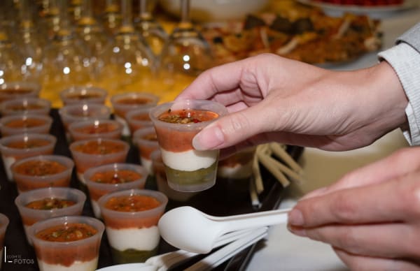 Gros plan sur une verrine apéritive à étages tenue à la main lors d'une dégustation, buffet traiteur événementiel