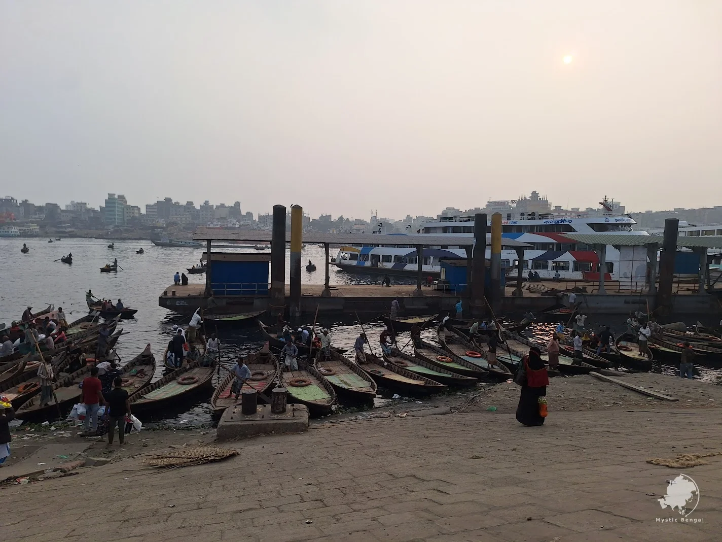 Buriganga River with boats and riverfront activity in Dhaka