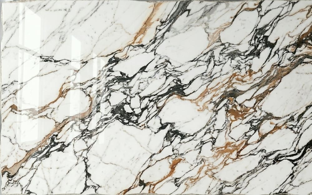Calacatta Sahara Noir marble — polished slab surface showing White coloring. Origin: Tunisia / Italy. Hardness: 3 Mohs. Acid sensitivity: high.