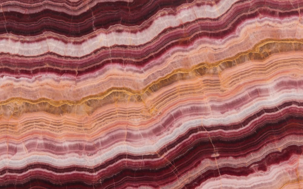 Pink Onyx onyx — polished slab surface showing Red/Pink coloring. Origin: Turkey / Iran. Hardness: 3 Mohs. Acid sensitivity: high.