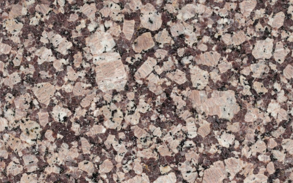 Rosa Porrino granite — polished slab surface showing Red/Pink coloring. Origin: Spain (Galicia — O Porriño). Hardness: 6 Mohs. Acid sensitivity: none.