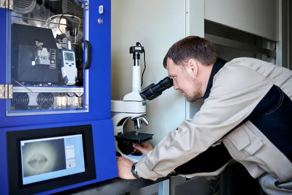 An engineer determines the structure of a substance by direct observation through a microscope in the petrochemical laboratory  of Neftekhim-Exp