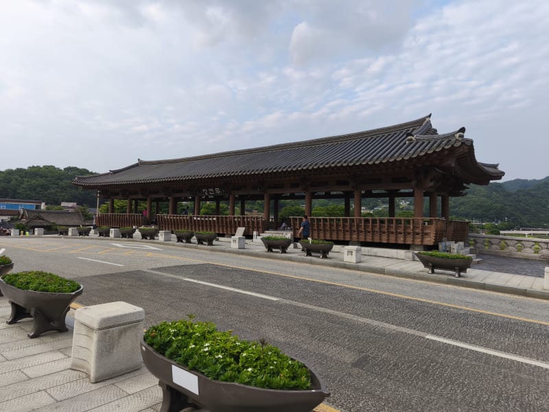 The elegant curved roof tiles of Cheongyeonnu Pavilion on Namcheon Bridge against the June sky