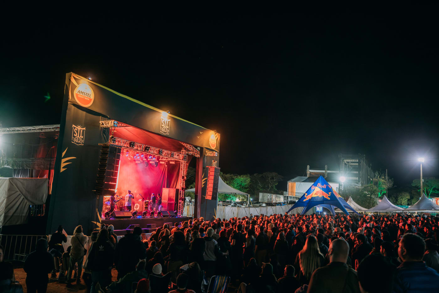 Palco iluminado à noite com show exclusivo, público curtindo a música e a energia do evento