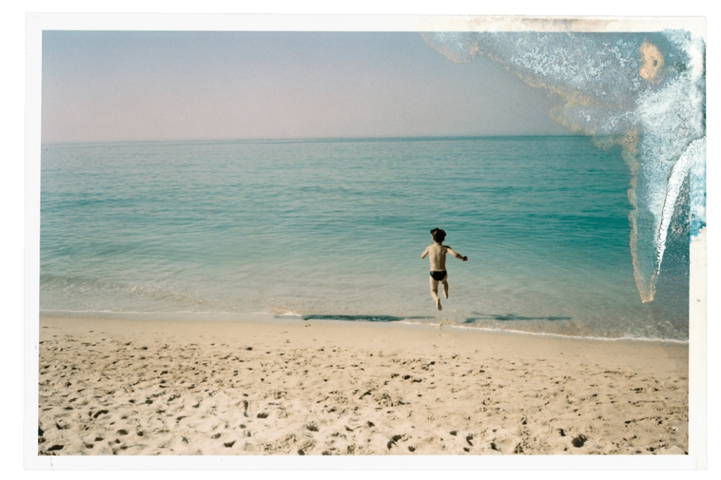 A child running into the sea, the print washed out at one corner.